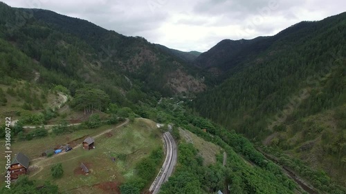 Aerial scene of small village in the uplands. Flying over green landscape, railway running across the mountains, Serbia. Part 2 photo