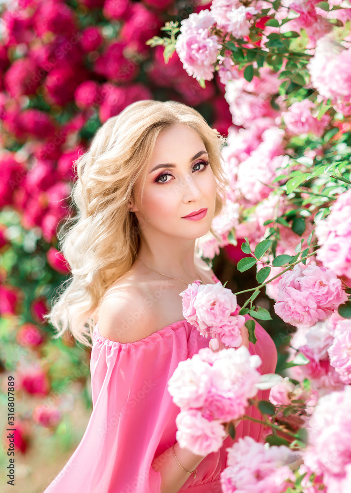 beautiful portrait of a blonde girl in pink roses. close-up, makeup, extended eyelashes