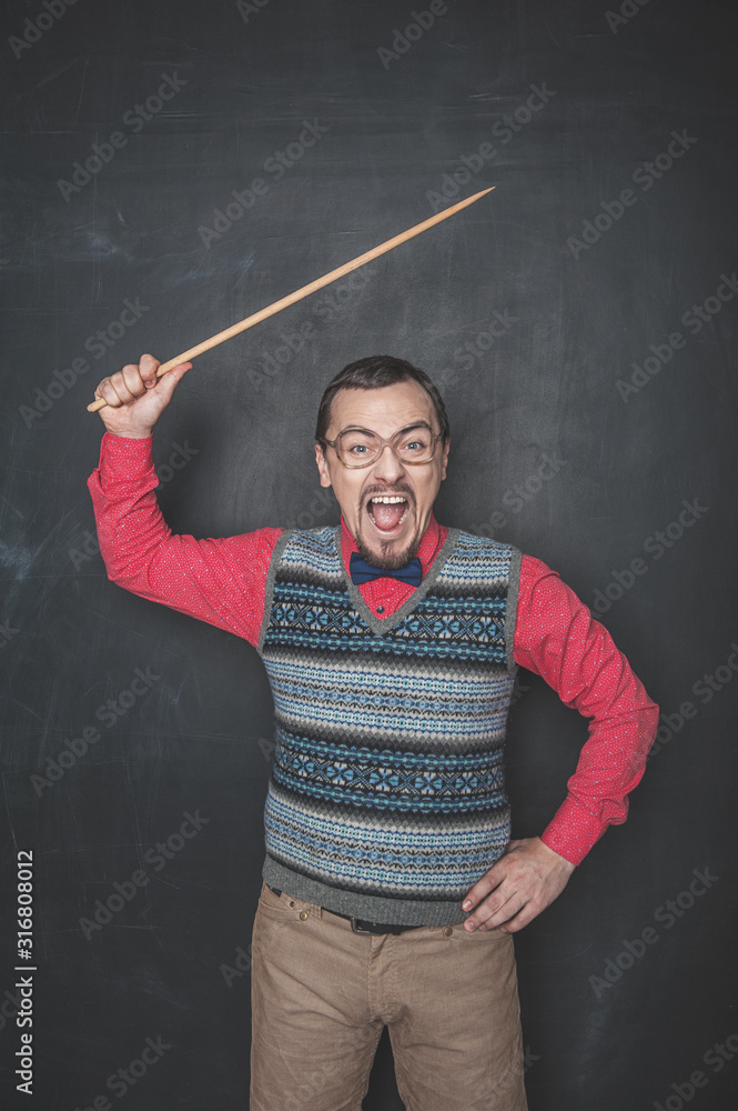 Angry business man or teacher with pointer on blackboard background