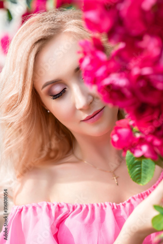 beautiful portrait of a blonde girl in pink roses. close-up, makeup, extended eyelashes