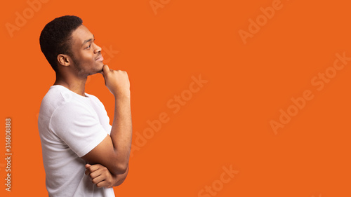 Pensive afro man profile portrait on orange background photo