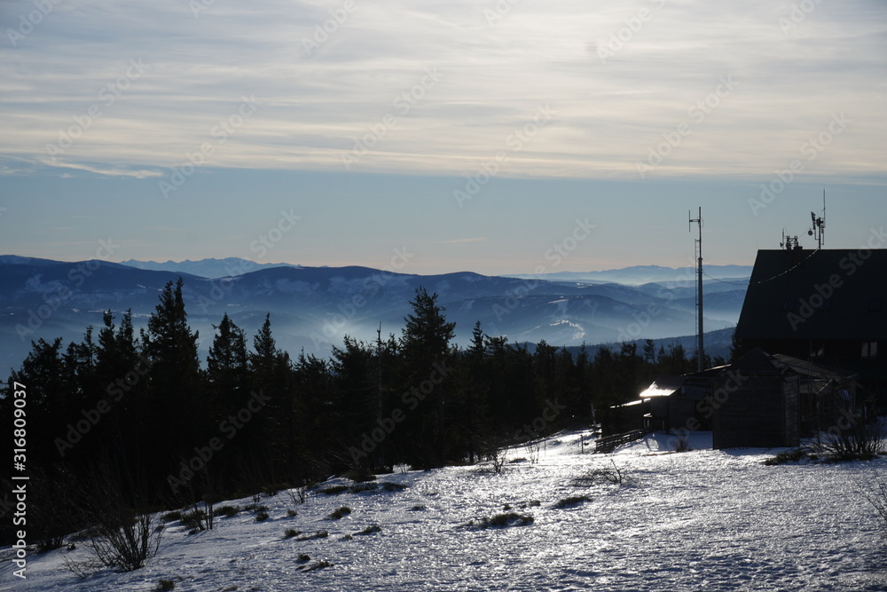 Panorama Beskid slaski . Mountain view from Skrzyczne peak in Szczyrk, Silesian region, Poland on a foggy and Sunny winter day. The mountains are partially covered with snow.