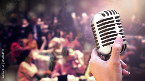 Retro microphone in women hand for speech or singing isolated on black background
