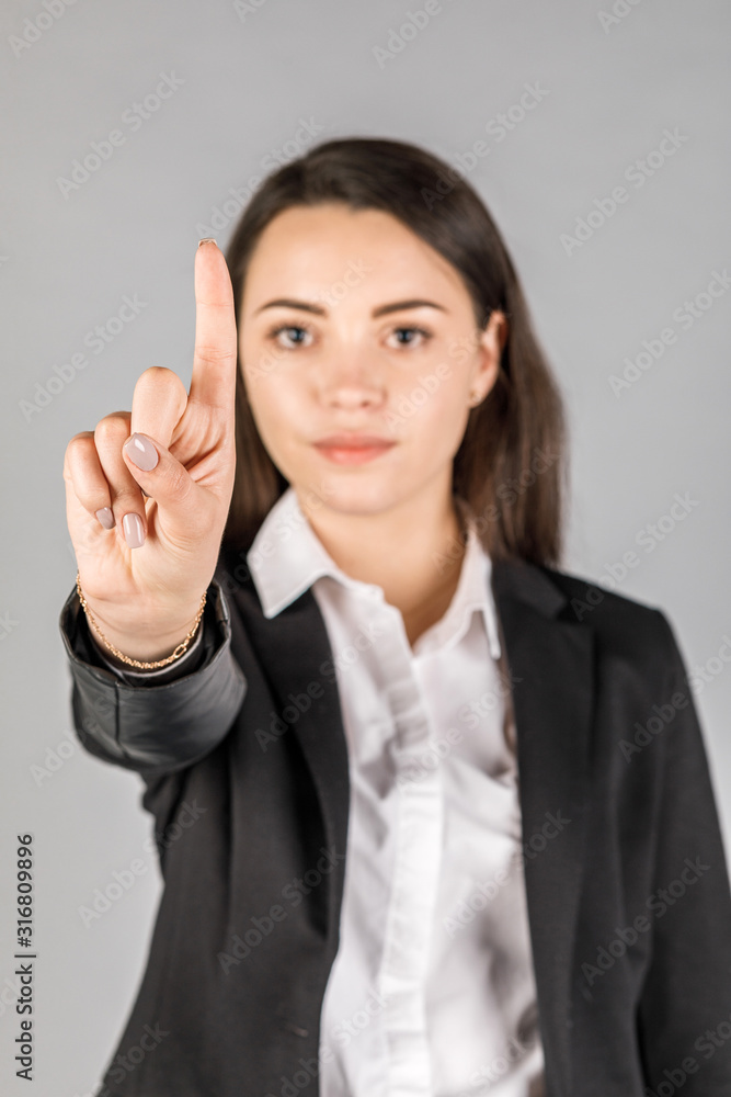 girl in black jacket on grey background showing finger girl in black jacket on grey background showing finger