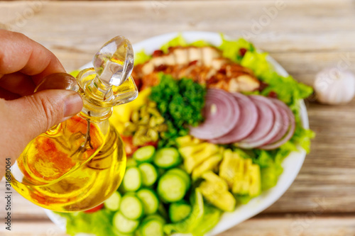 Woman holds olive oil for vegetable salad.