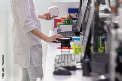 Pharmacist holding medicine box and capsule pack in pharmacy drugstore.