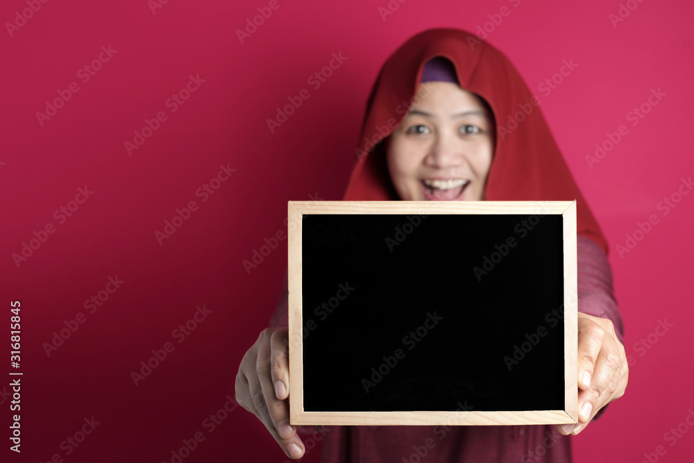 Smart Asian Muslim Woman Smiling at Camera and Showing Empty Blackboard Smart Asian Muslim Woman Smiling at Camera and Showing Empty Blackboard