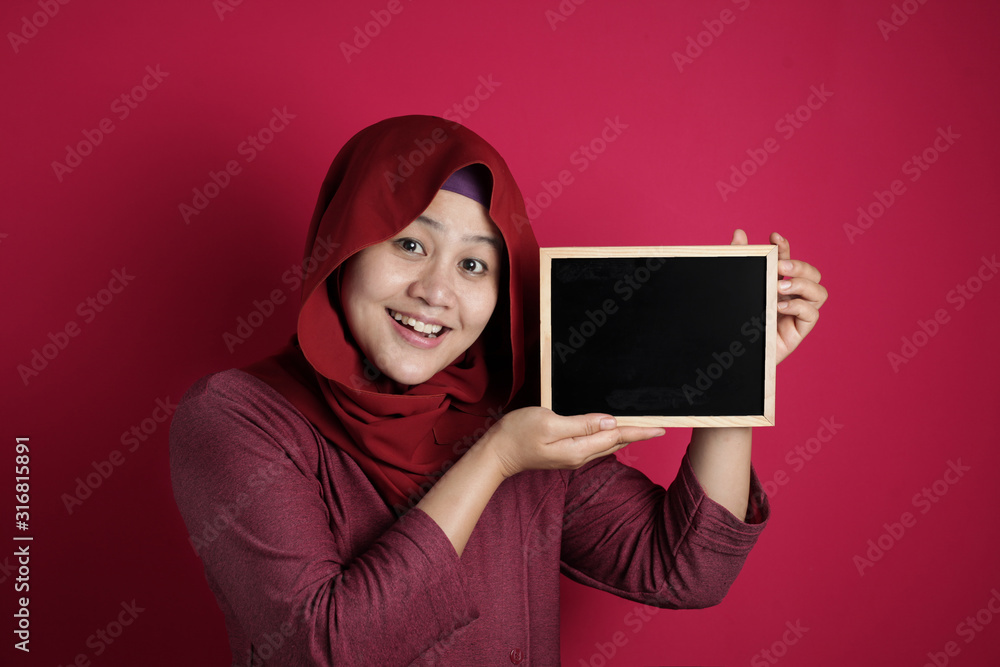 Smart Asian Muslim Woman Smiling at Camera and Showing Empty Blackboard Smart Asian Muslim Woman Smiling at Camera and Showing Empty Blackboard