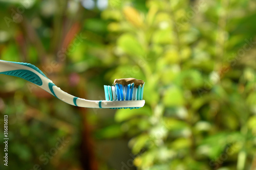Toothbrush in hand with greenish blurred background. blue toothbrush.