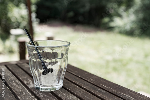 empty glass with ice cubes. On wooden table in garden