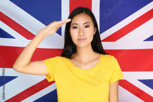 Young woman saluting with hand on British flag background