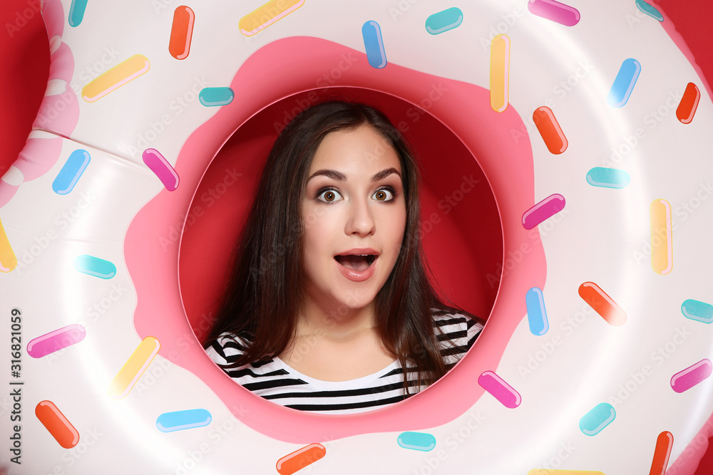Fototapeta premium Young girl with inflatable donut on red background