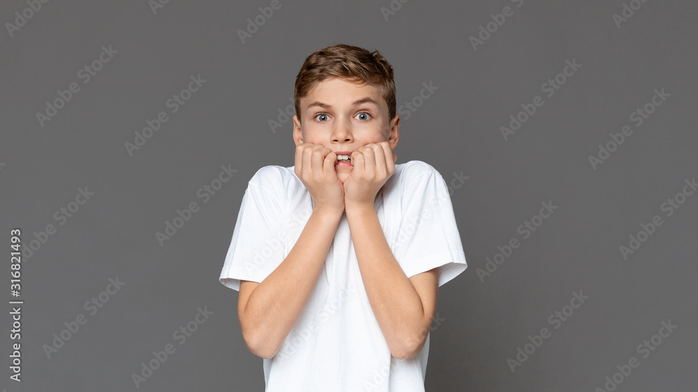 Scared teen boy biting nails in fear Scared teen boy biting nails in fear