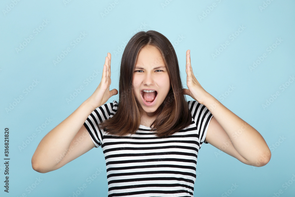 Young angry girl on blue background