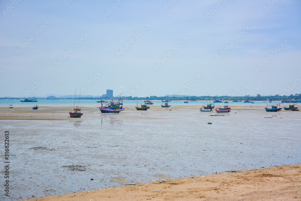 Fishing boat parked on the beach,Fishing boat parked on the seashore,Small fishing boat parked and moored on the beach at low tide. Boat and anchor at the beach in summer vacation. Sunny day. Fishing boat parked on the beach,Fishing boat parked on the seashore,Small fishing boat parked and moored on the beach at low tide. Boat and anchor at the beach in summer vacation. Sunny day.