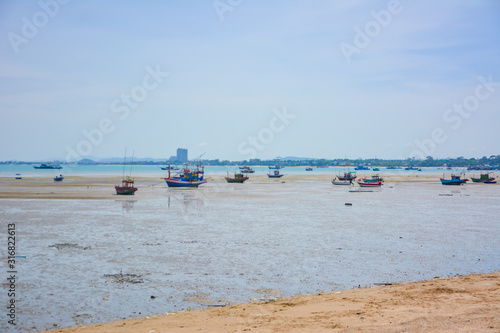 Fishing boat parked on the beach,Fishing boat parked on the seashore,Small fishing boat parked and moored on the beach at low tide. Boat and anchor at the beach in summer vacation. Sunny day. © kidsasarin
