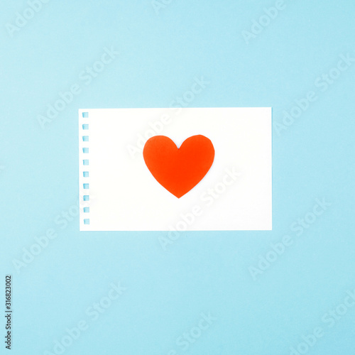 Delicate blue background with a white Notepad sheet and a heart.