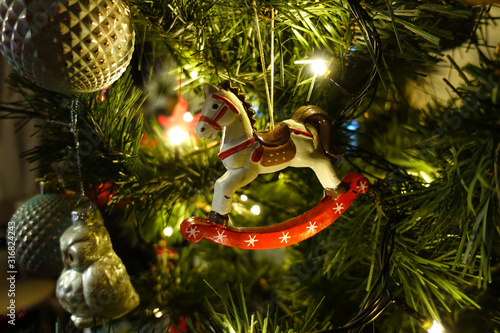 Decorated Christmas tree closeup. Red and golden balls and illuminated garland with flashlights. New Year baubles macro photo with bokeh. Winter holiday light decoration