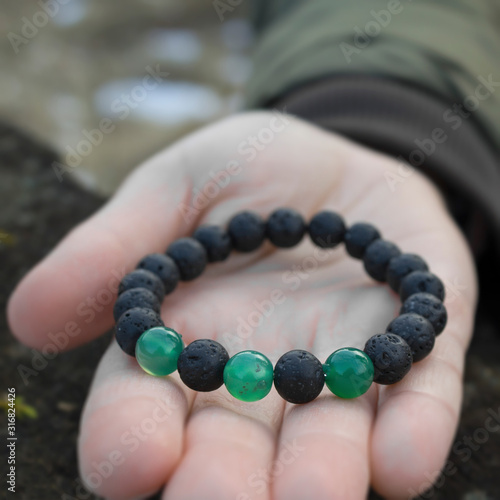 Black lava stone bracelet lies in the open hand.