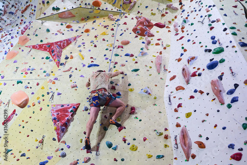 Unrecognizable man climbing wall in bouldering gym