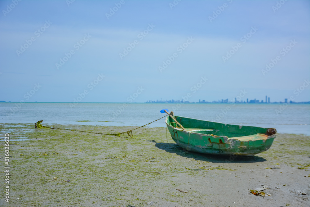 Fishing boat parked on the beach,Fishing boat parked on the seashore,Small fishing boat parked and moored on the beach at low tide. Boat and anchor at the beach in summer vacation. Sunny day.