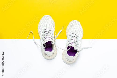 White running shoes on an abstract yellow-white background. Concept of running, training, sport. Banner. Flat lay, top view