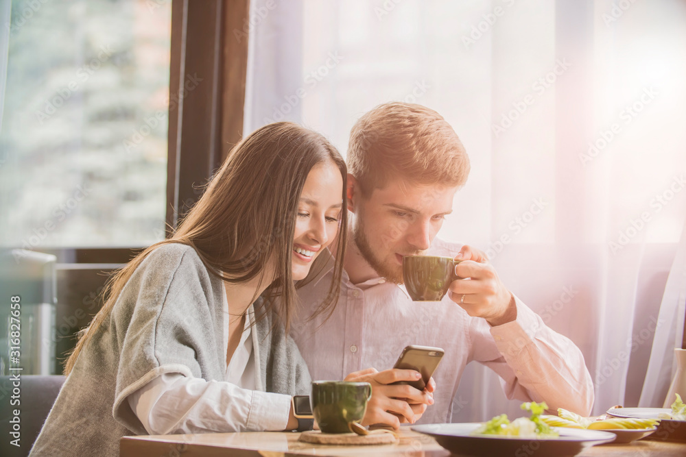 couple in a cafe smiling looking at the phone