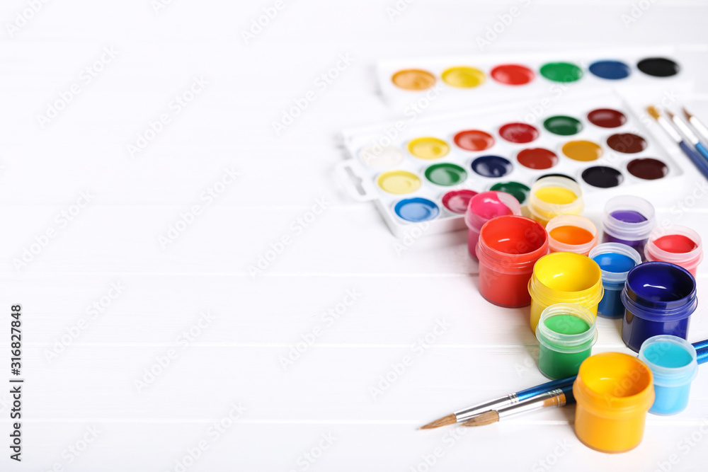 Colorful gouache paints and brushes on white wooden table Colorful gouache paints and brushes on white wooden table