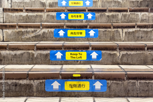 Stairs with signs in various Asian languages that read Keep to the Left