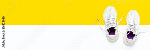 White running shoes on an abstract yellow-white background. Concept of running, training, sport. Banner. Flat lay, top view