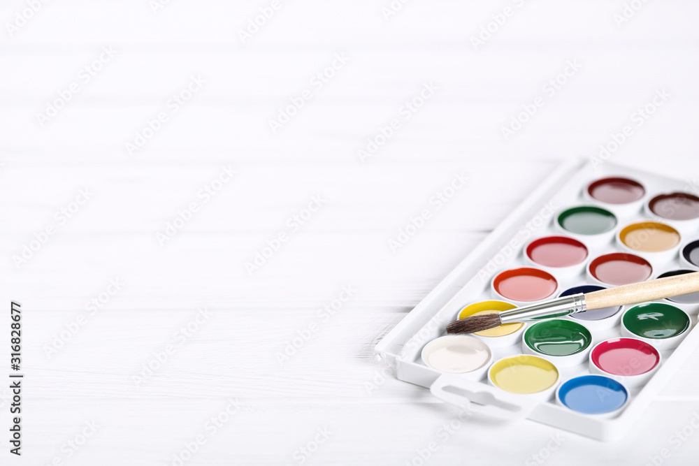 Colorful gouache paints and brush on white wooden table Colorful gouache paints and brush on white wooden table