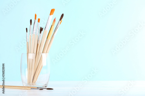 Artistic brushes in glass on blue background