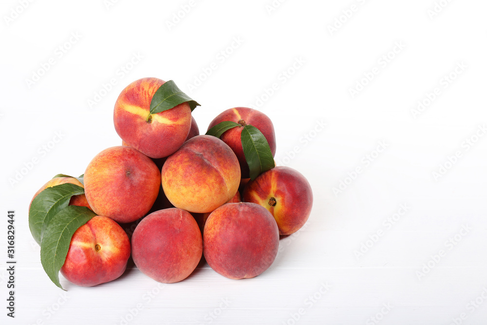 Fresh peaches with green leafs on white wooden table Fresh peaches with green leafs on white wooden table