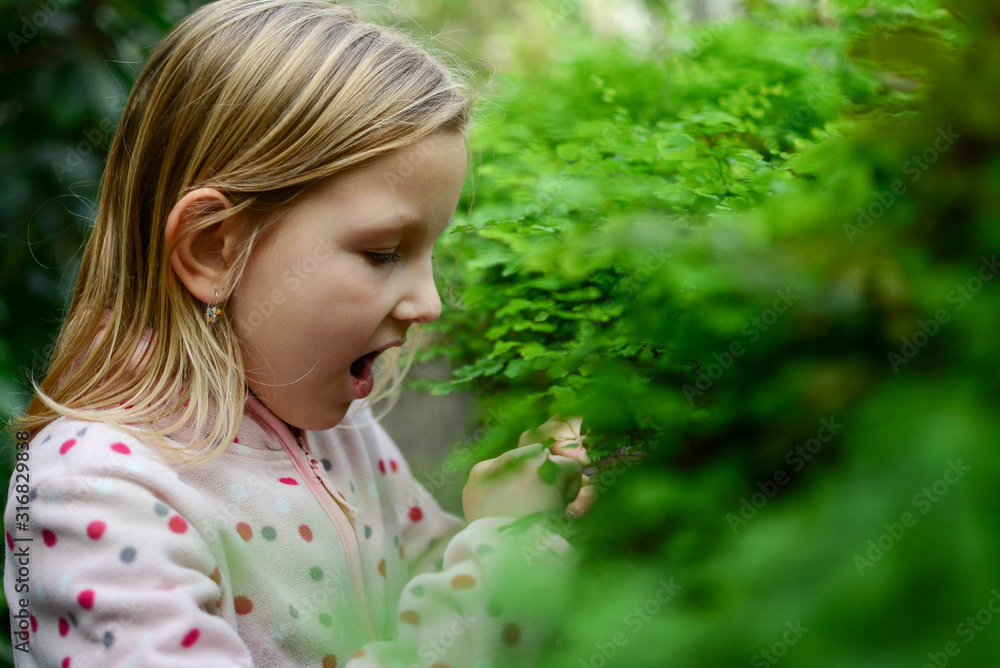 Cheerful cute girl playing and explore in glass garden. Beautiful expressive adorable happy cute laughing smiling girl in secret garden. Children, people, preschool and greenhouse concept