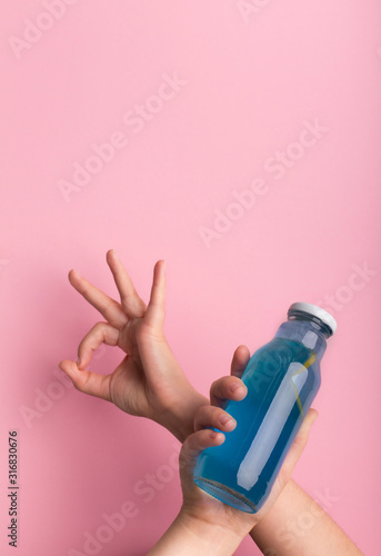 Female holding bottle with blue isodrink water and showing ok sign