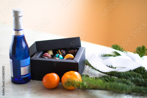 new year presents on the table. blue bottle of champagne, candys and mandarin