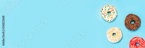 Tasty donuts of different types on a blue background. Concept of sweets, bakery, pastries. Banner. Flat lay, top view