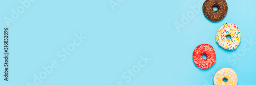 Tasty donuts of different types on a blue background. Concept of sweets, bakery, pastries. Banner. Flat lay, top view