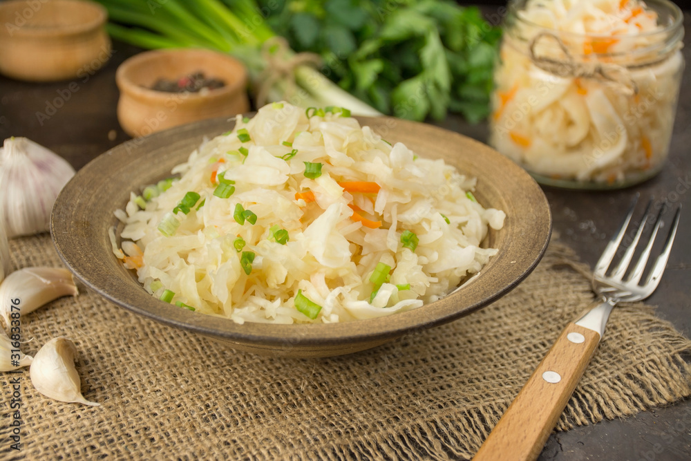 Sauerkraut with carrots in a bowl. Homemade food. Sour food. Pickled vegetables. Vegetarian vegan food. Side view . Sauerkraut with carrots in a bowl. Homemade food. Sour food. Pickled vegetables. Vegetarian vegan food. Side view .