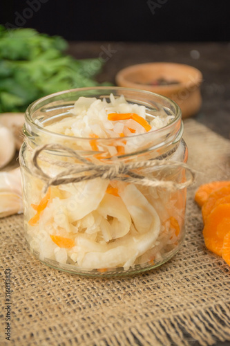 Sauerkraut with carrots in a small jar. Homemade food. Sour food. Pickled vegetables. Vegetarian vegan food. Side view .