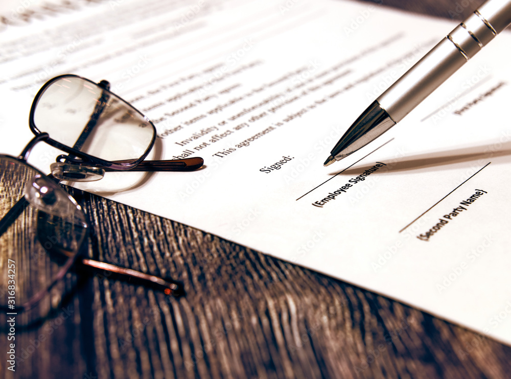 Fototapeta premium Contract sheet with glasses and pen on a wooden background