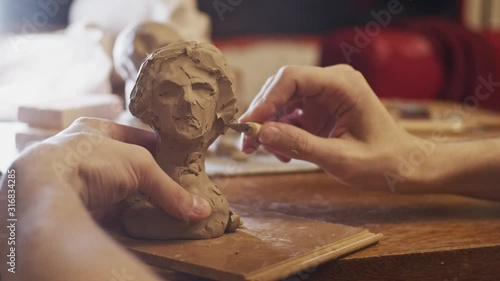 Young artist sculpting bust of woman from real young woman using Plasticine (non-drying clay)