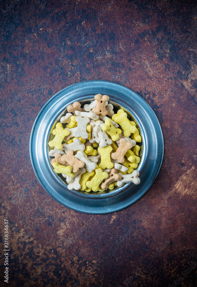dry pet food in a metal bowl on lava background, top view dry pet food in a metal bowl on lava background, top view