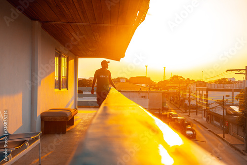 Tela, Honduras »; January 2020: A young man in a sunset from the city of Tela in a sunset photo