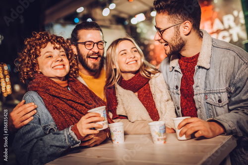 Friends drinking hot wine and having fun on outdoor concert. Celebrating new year