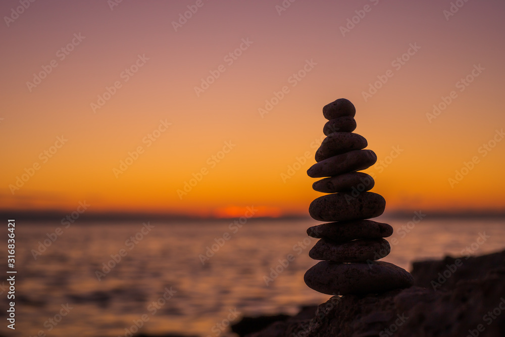 Fototapeta premium The object of the stones on the beach at sunset. Zen concept. Sunset. Silhouette of stones against the sunset sky
