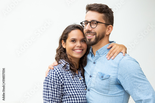 Happy young couple standing and embracing. Beautiful cheerful young couple hugging and smiling at camera on white background. Closeness concept