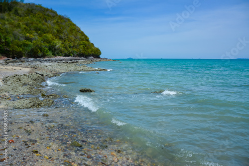 Beautiful rock beach with sea ocean and mountain blue sky landscape background,An island in the sea with beaches, rocks and turquoise water in the hot summer sun of Thailand.