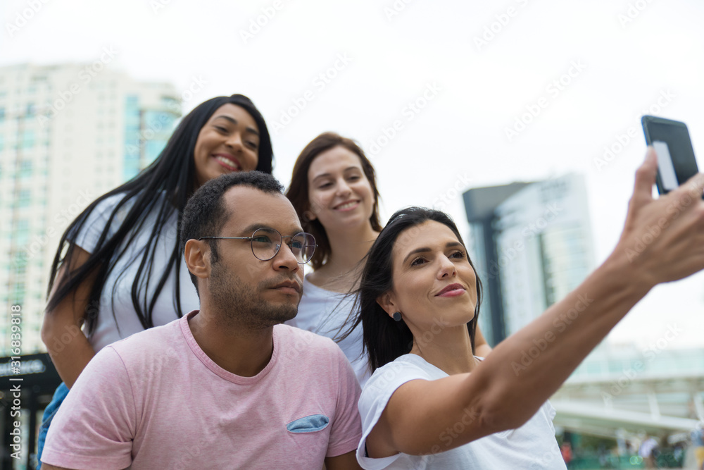 Group of friends taking selfie with smartphone on street. Cheerful young people posing for self portrait. Concept of self portrait