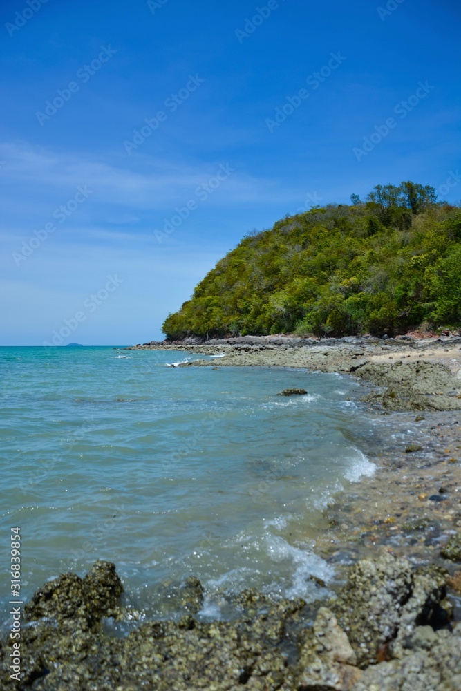 Beautiful rock beach with sea ocean and mountain blue sky landscape background,An island in the sea with beaches, rocks and turquoise water in the hot summer sun of Thailand.